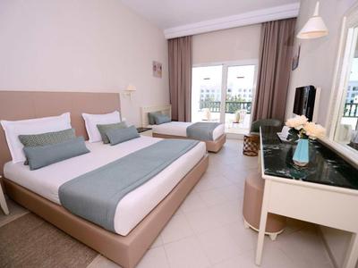 Moderní hotelový pokoj se dvěma postelemi, velkým zrcadlem a přístupem na balkon.