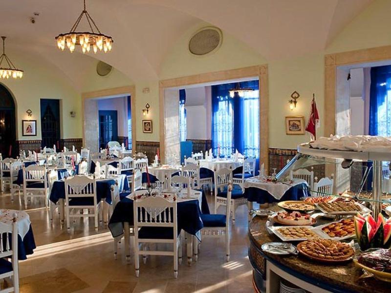 Ristorante elegante con sedie bianche, tovaglie blu e buffet con dolci.