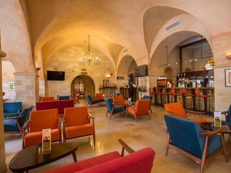 Ampia lounge dell'hotel con soffitti ad arco, poltrone colorate e un bar ben illuminato.