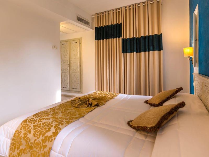 Una camera da letto elegantemente arredata con letto, copriletto dorato e tende.