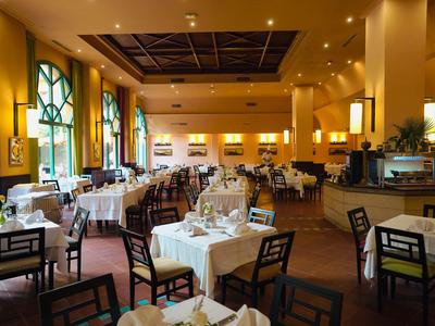 Ristorante elegante con tovaglie bianche e sedie di legno in una stanza caldamente illuminata.