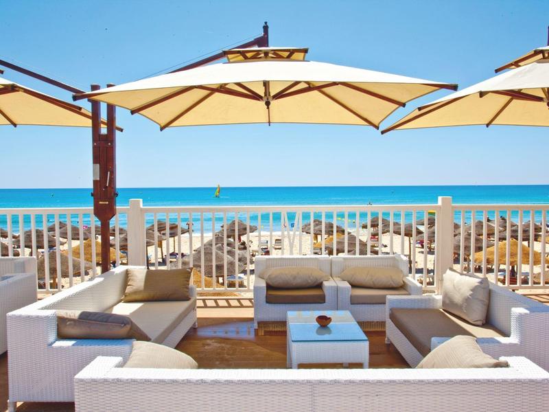 Grupo moderno de asientos lounge con sombrillas en la playa bajo cielo despejado.