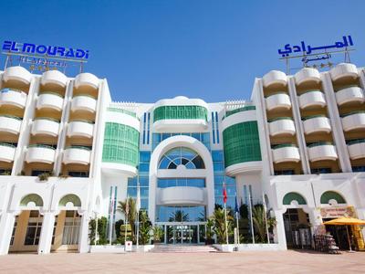 Modernes Hotelgebäude mit weißen Balkonen und blauen Beschilderungen unter klarem Himmel.