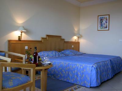 Hotelzimmer mit zwei Betten, Sitzbereich und gedecktem Tisch mit Weinflaschen