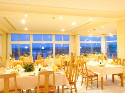 Jasně osvětlená jídelna s prostřenými stoly a velkými okny s výhledem na město.