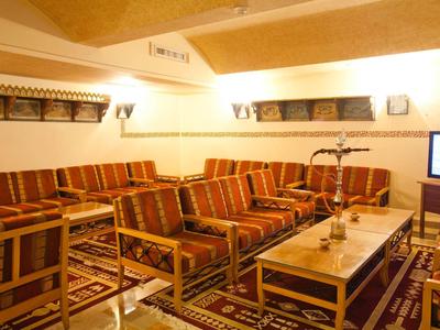 Pohodlná sedací zóna s křesly a pohovkami kolem stolů v teple osvětlené místnosti.