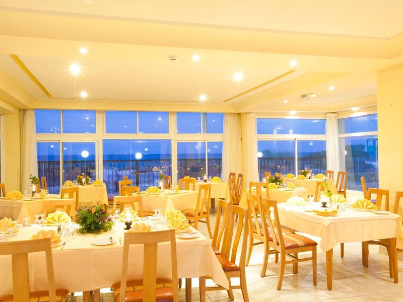 Jasně osvětlená jídelna s prostřenými stoly a velkými okny s výhledem na město.