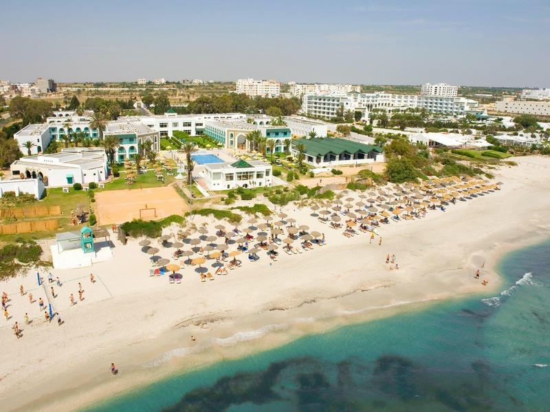 Přímořské letovisko s lehátky, slunečníky a čistou vodou u moře.