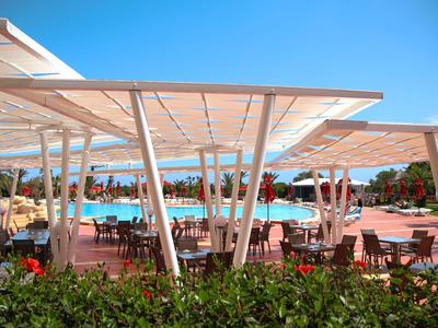 Modernes Pool-Außenbereich mit schattigem Sitzbereich unter Pergolen und klar blauem Himmel.