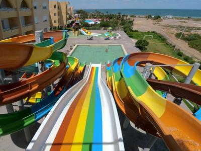 Bunte Wasserrutschen führen zu einem Schwimmbecken in einem Hotel mit Blick auf das Meer.