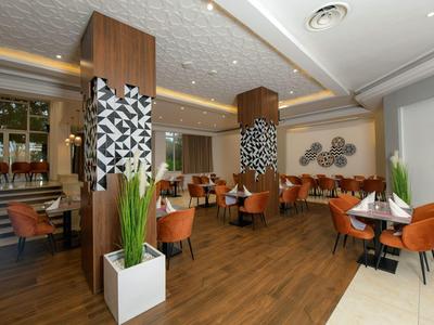 Moderní hotelová restaurace s hnědými židlemi a dekorativními sloupy.