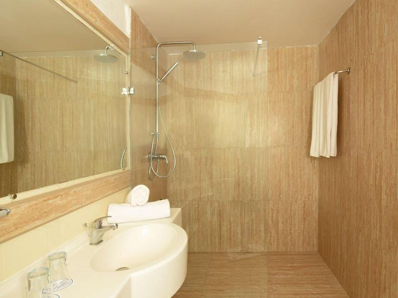 Moderní koupelna s velkou zrcadlovou stěnou, bílými umyvadly a béžovým sprchovým koutem.