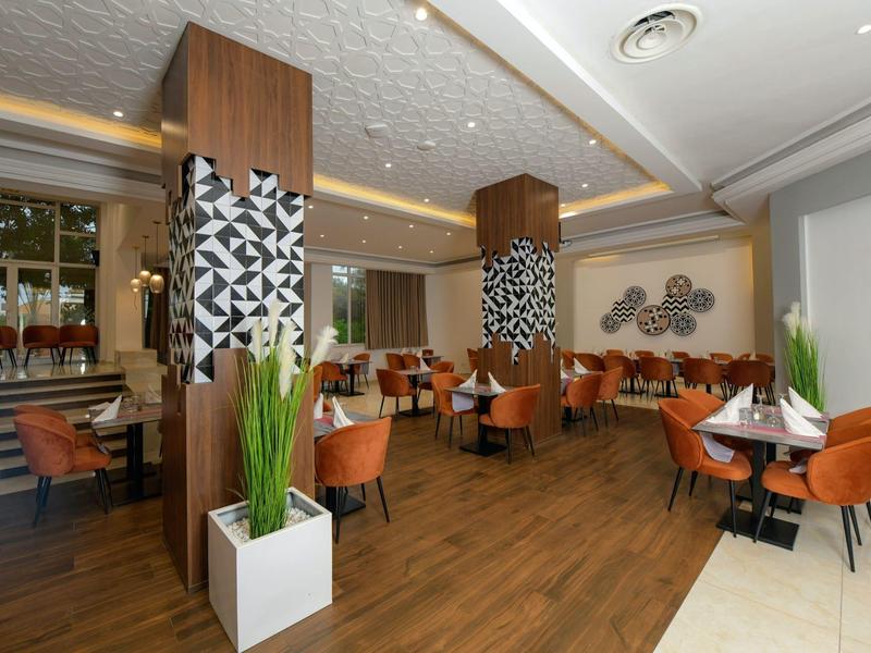 Moderní hotelová restaurace s hnědými židlemi a dekorativními sloupy.