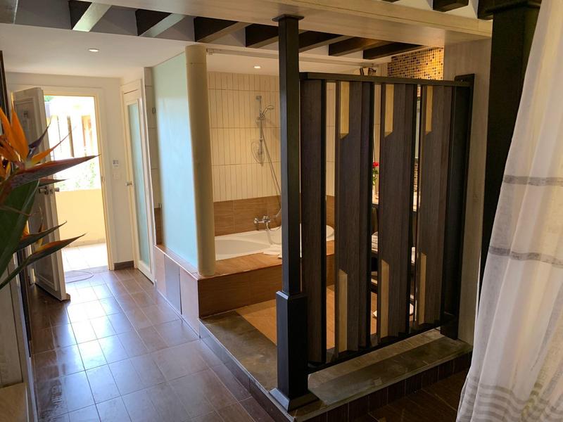 Moderner Hotelbadezimmer mit Holzakzenten und getrennter Badewannen- und Duschbereich.