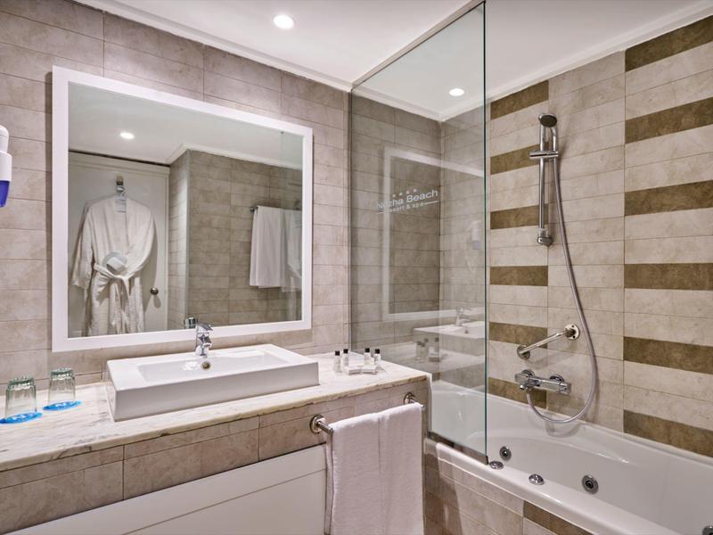 Moderner Badezimmerbereich mit Waschbecken, beleuchtetem Spiegel und Dusche mit Glaswand.