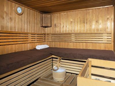 Sauna wyłożona drewnem z brązowymi ręcznikami, drewniane wiadro i chochla pod drewnianymi panelami.