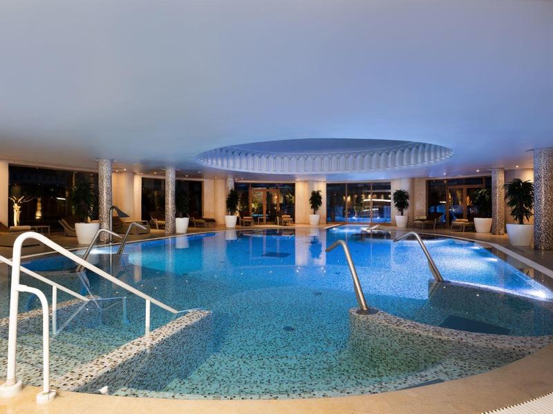 Nowoczesny kryty basen z fotelami i eleganckim oświetleniem w hotelu.