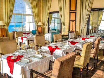 Elegantní restaurace s prostřenými stoly, velkými okny a výhledem na moře.