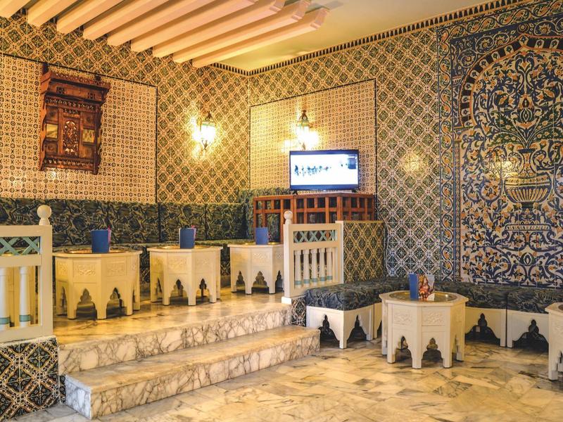 Tradiční místnost s dlaždicemi, lavicemi a televizí.