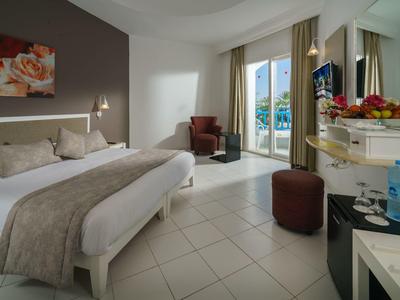 Moderně zařízený hotelový pokoj s velkou postelí, balkonem a posezením.