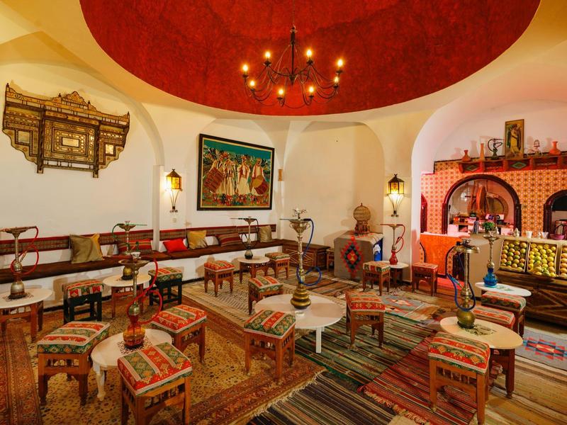 Pohodlná orientální místnost s polštáři, koberci a teplým osvětlením.