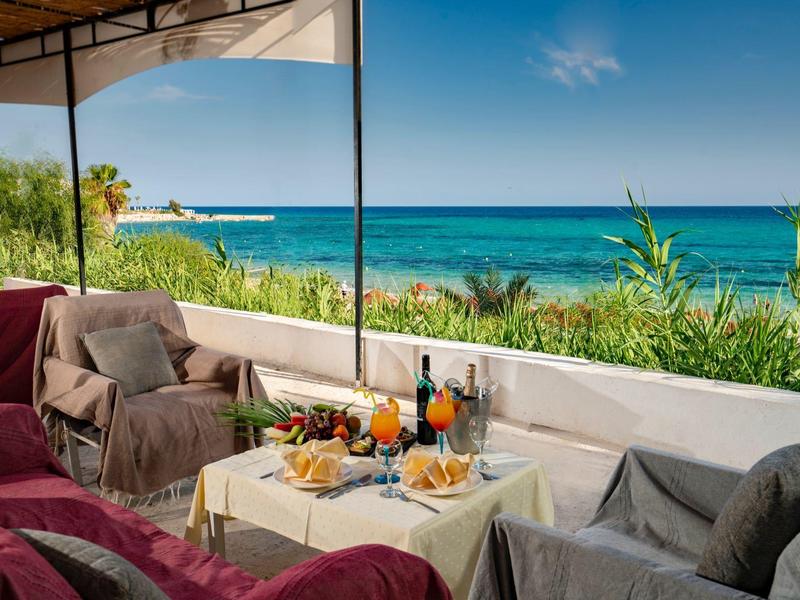 Gezellig terras met tafels, stoelen en uitzicht op zee op een zonnige dag.