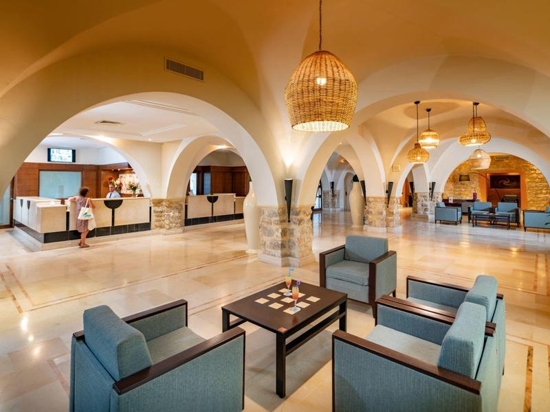 Ruime hotel lobby met zitgedeeltes, incheckbalies en gewelfde plafonds.