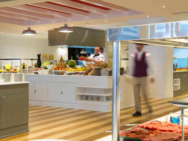 Nowoczesna kuchnia hotelowa z kucharzem i kelnerem przygotowującymi jedzenie i obsługę