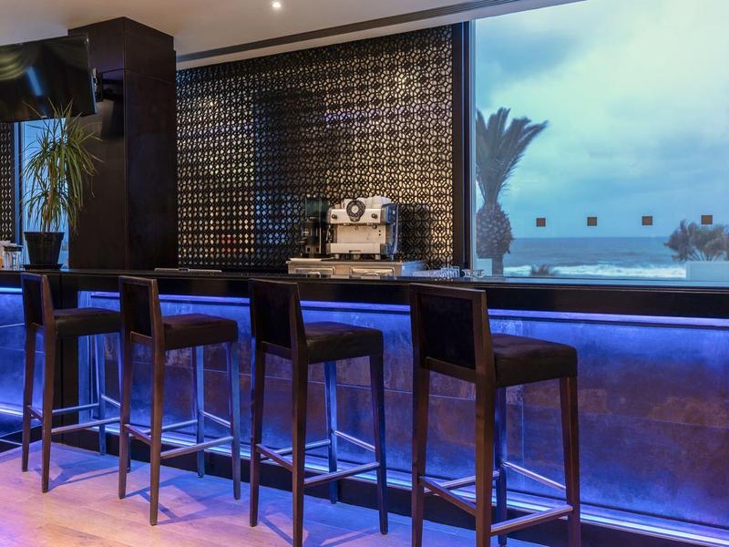 Nowoczesny bar hotelowy z wysokimi stołkami i niebieskim oświetleniem