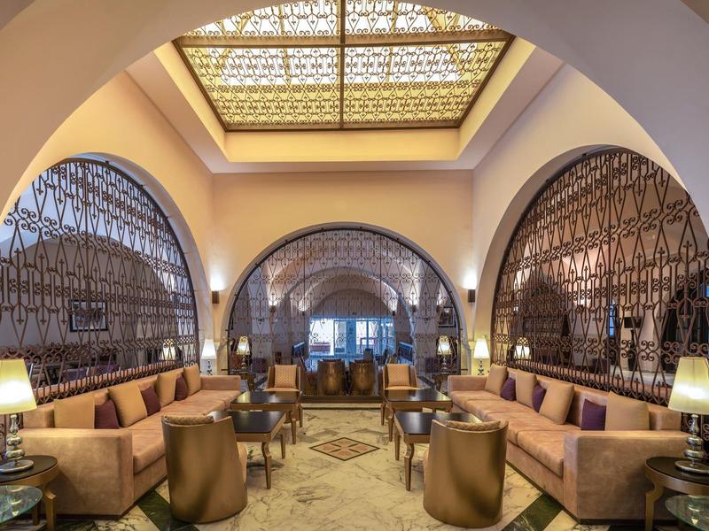 Elegancki salon hotelowy z zakrzywionymi łukami, wygodnymi sofami i ciepłym oświetleniem.