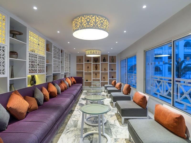 Nowoczesny salon hotelowy z fioletowymi sofami i dekoracyjnymi poduszkami