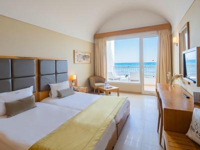 Světý hotelový pokoj se dvěma jednolůžky, výhledem na moře a balkonem.