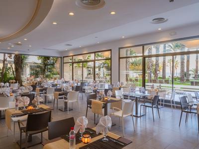 Světla, moderní restaurace s elegantně prostřenými stoly a velkými okny s výhledem do zahrady.