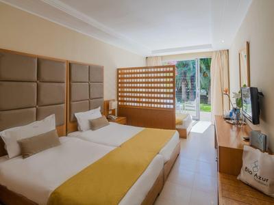 Moderní hotelový pokoj se dvěma jednolůžky, dřevěným nábytkem a výhledem na zahradu.