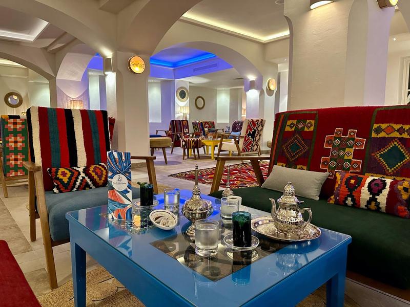 Pohodlný kout s pohovkou, barevnými polštáři a čajovým servisem na stole v teple osvětlené místnosti.