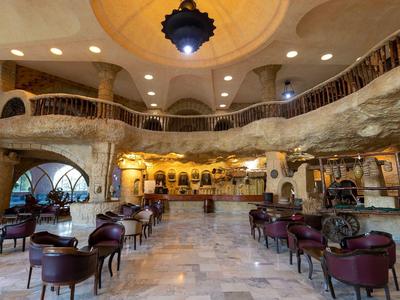 Prostorná hotelová hala s kulatými židlemi, dekorativním stropem a přirozeným osvětlením.