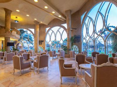 Espace lounge d'hôtel élégant avec grandes fenêtres cintrées et fauteuils confortables.