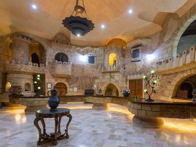 Grande salle en pierre avec des arches ornées, meubles anciens et éclairage d'ambiance.