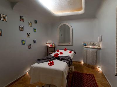 Klidná wellness místnost s masážním stolem, dekorativními květinami a měkkým osvětlením.