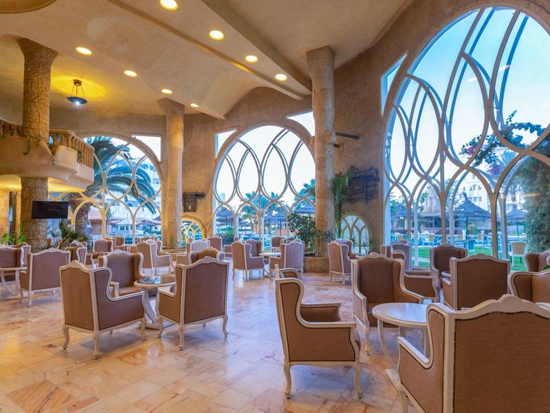 Světlá, moderní hotelová jídelna s velkými okny a pohodlnými židlemi.