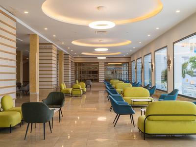 Moderní hotelová lounge oblast se zelenými a modrými křesly a velkými okny