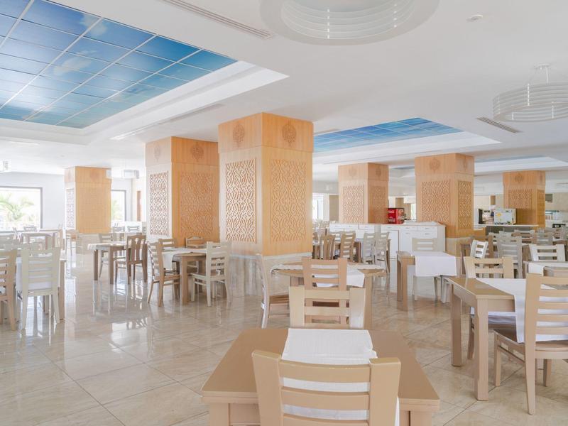 Sala da pranzo luminosa e moderna con mobili in legno e grandi finestre in un hotel.