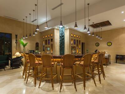 Prostorná, teple osvětlená restaurace s dřevěnými židlemi kolem stolů a závěsnými světly.