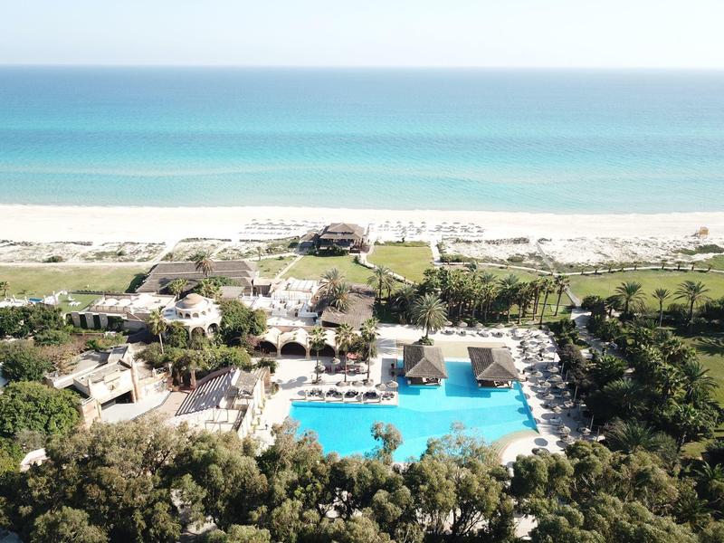 Luxusní plážové letovisko s velkým bazénem, lehátky a výhledem na oceán.