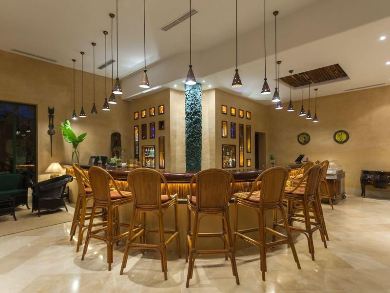 Prostorná, teple osvětlená restaurace s dřevěnými židlemi kolem stolů a závěsnými světly.