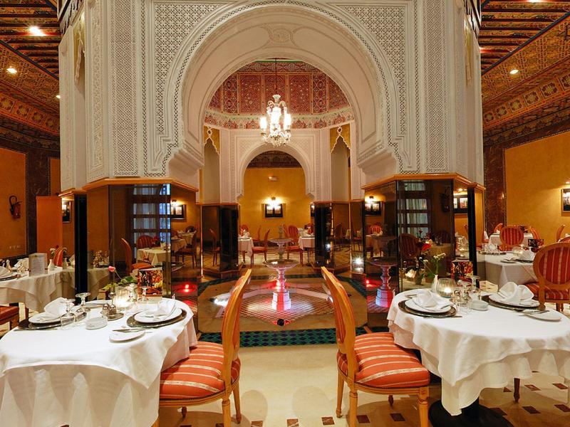 Ristorante elegante con tavoli coperti di bianco e architettura araba all'interno.
