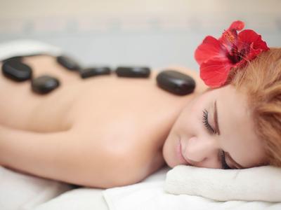 Donna che si rilassa durante un massaggio con pietre calde con pietre nere sulla schiena.