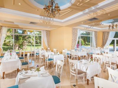 Ristorante elegante con tavoli bianchi e grandi finestre con vista su giardino e acqua