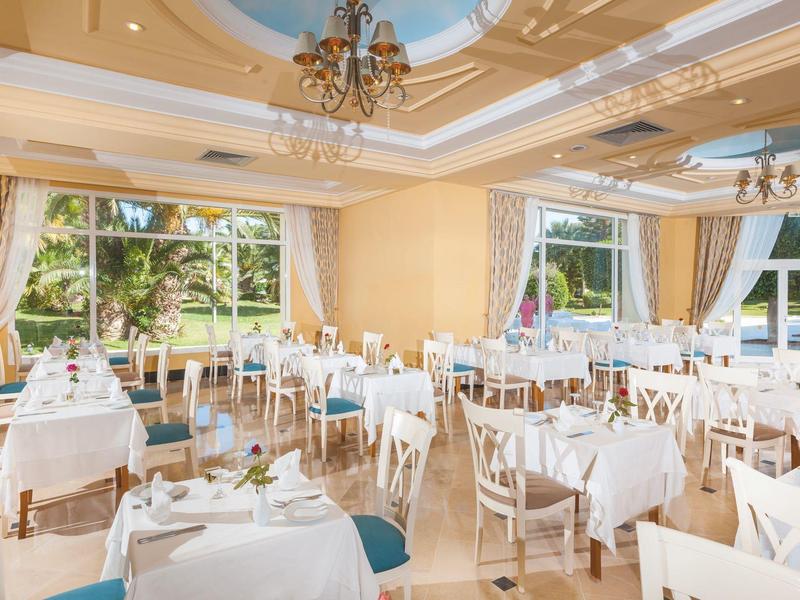 Ristorante elegante con tavoli bianchi e grandi finestre con vista su giardino e acqua