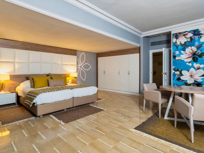 Camera d'hotel moderna con letto matrimoniale, scrivania e grande stampa floreale sulla parete.